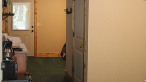 Um corredor com piso em carpete, uma porta com moldura de madeira e um radiador na parede.