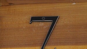 Uma porta de madeira com uma placa de metal com o número 7.
