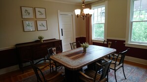 A dining room with a rectangular table, six chairs, a chandelier, and framed botanical prints on the wall. - Governor's Home (Historic Property) (Cheyenne)