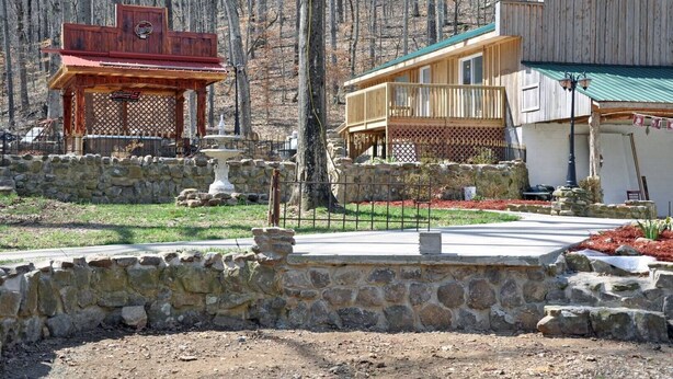Un chalet rustique avec des fondations en pierre, une terrasse en bois et un petit kiosque.