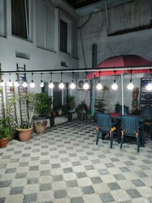 Relax under the stars with a table and chairs set amidst lush greenery and twinkling string lights.