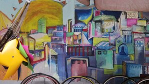 Um mural colorido com edifícios e um pássaro amarelo.