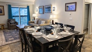 A dining area with a table set for four, a sofa, and a chair with a cushion. - Snowblaze 310 Cozy Comfort in the Heart of Park City (Park City)