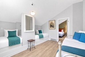 Une chambre d’hôtel avec deux lits, une petite table, un miroir et un tableau au mur.