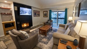 A living room with a fireplace, a sofa, a coffee table, and a TV. - Snowblaze 310 Cozy Comfort in the Heart of Park City (Park City)