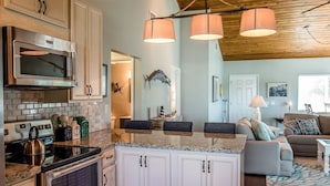 A kitchen with white cabinets, a microwave, and a stove. There are three pendant lights hanging from the ceiling. - FALL SEASON 55% OFF RENTAL RATE (Marathon)