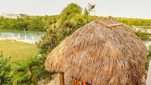 A thatched-roof structure with a pool and bar area, surrounded by greenery and a view of a water body. - FALL SEASON 55% OFF RENTAL RATE (Marathon)