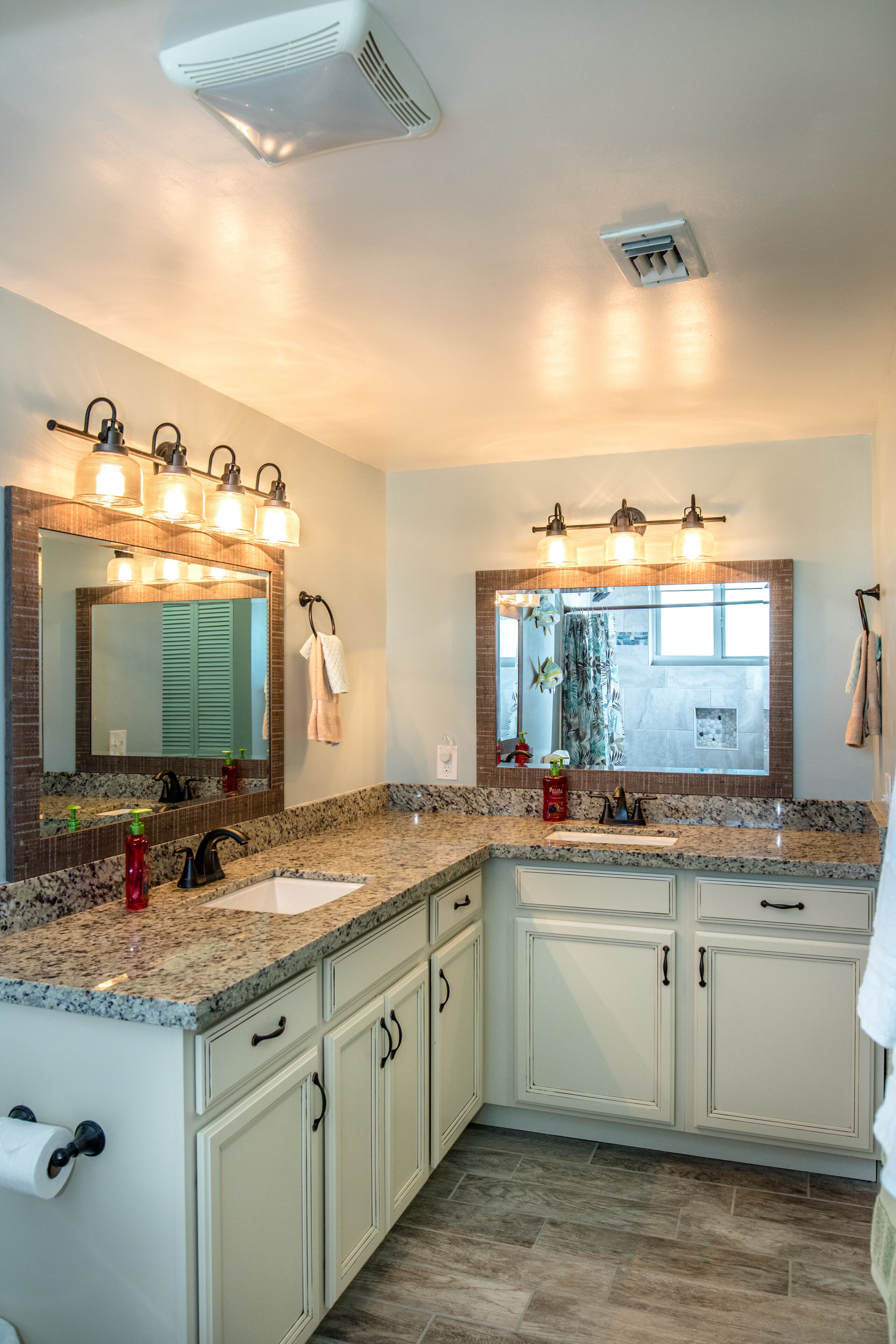 A bathroom with two sinks, a large mirror, and a ceiling vent.