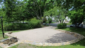A gravel driveway with a stone border, surrounded by grass and trees.