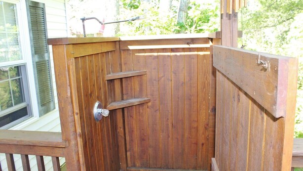 A wooden outdoor structure with a door, a window, and a metal tool on top.