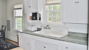 A modern kitchen with white cabinetry, a granite countertop, a built-in sink, a toaster, and a coffee maker.