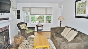 A living room with a fireplace, a sofa, a chair, a coffee table, and a window with blinds.