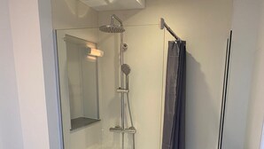 Un baño moderno con ducha acristalada, inodoro y barra para toallas.