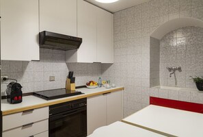 Een koelkast, een oven, een vaatwasser, kookgerei, borden en bestek