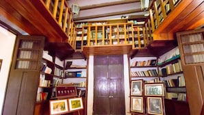 A library with wooden bookshelves, a central door, and framed pictures on easels. - HACIENDA Blanca Flor CAMINO REAL (Hecelchakan)