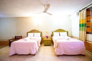 A hotel room with two beds, a ceiling fan, a nightstand with a lamp, and a window with curtains. - HACIENDA Blanca Flor PIEZA ORO VERDE (Hecelchakan)