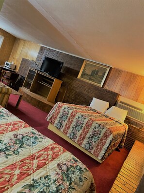 Une chambre d’hôtel avec deux lits, une télévision, un bureau et un tableau au mur.