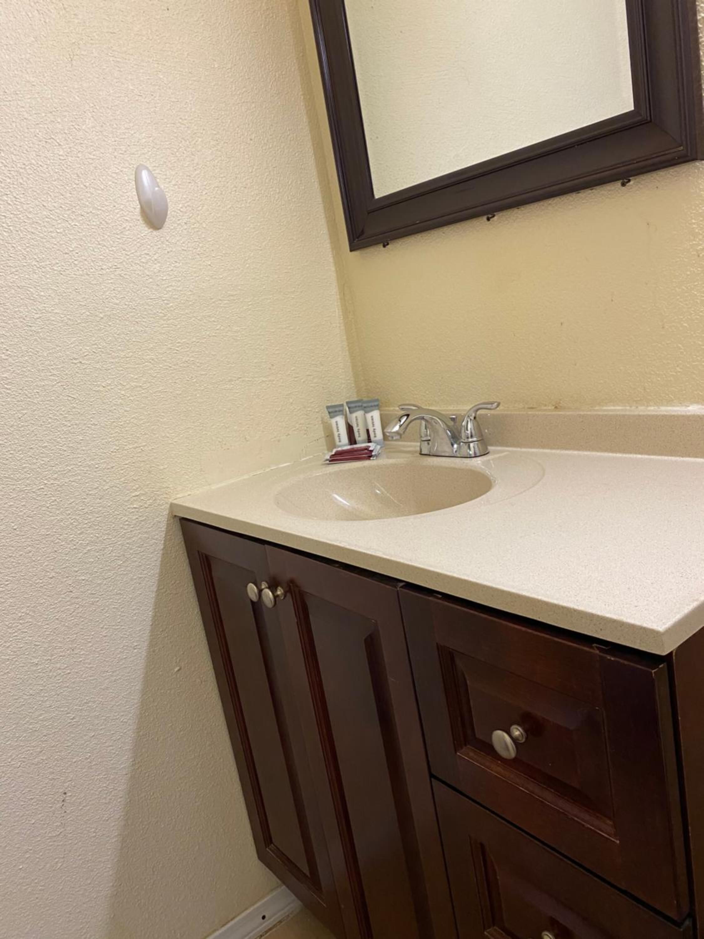 A bathroom with a sink, mirror, and cabinets.