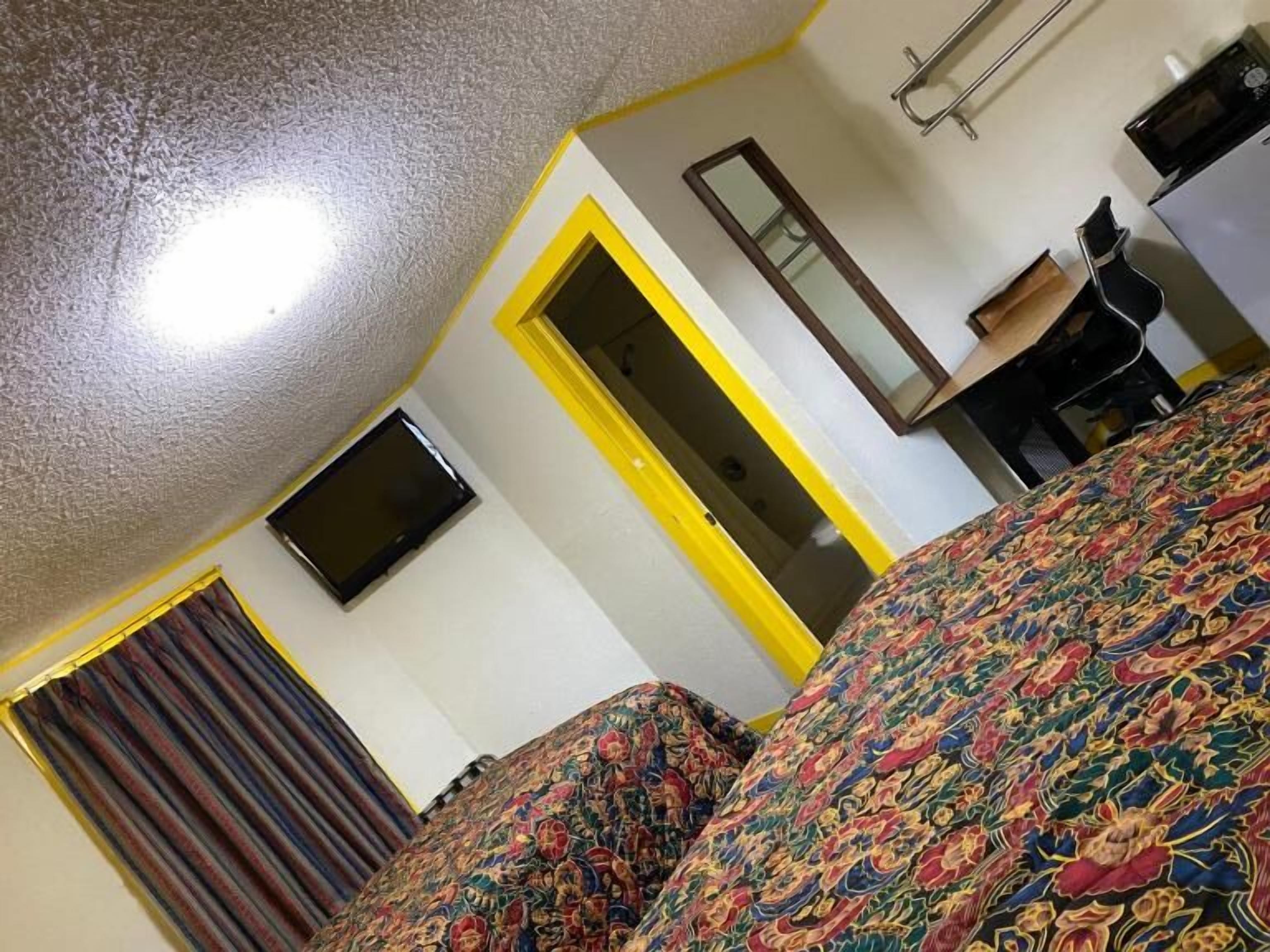 A hotel room with a bed, a television, a desk, and a mirror.