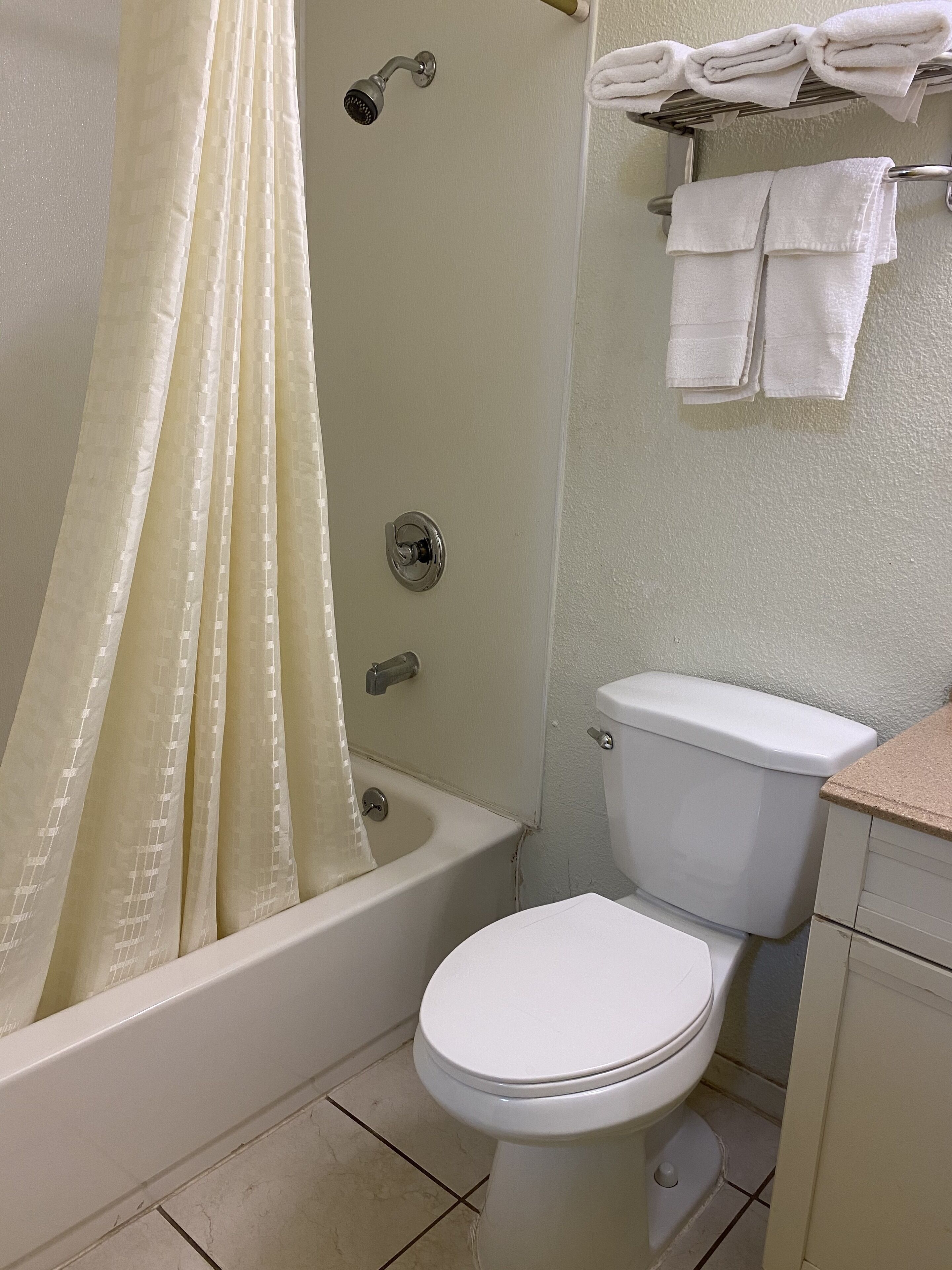 A bathroom with a bathtub, toilet, and a towel rack with folded towels.