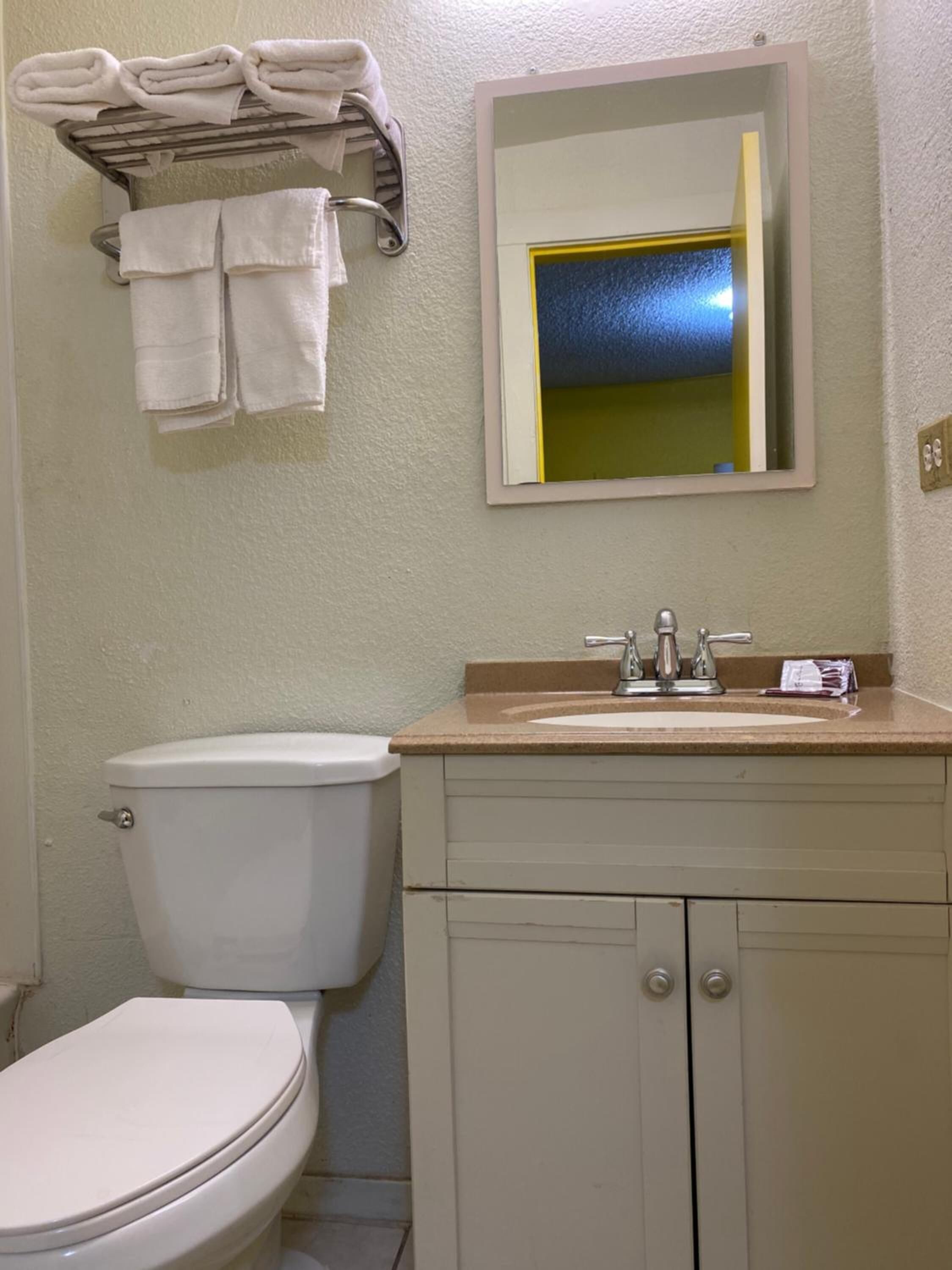 Une salle de bain équipée de toilettes, d’un lavabo et d’un porte-serviettes.