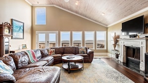 A spacious living room with a large sectional sofa, a fireplace, and a television. - Beachfront Home Perfect For Family Vacations (Galveston)