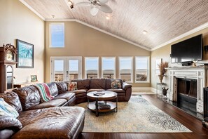 A spacious living room with a large sectional sofa, a fireplace, and a television.