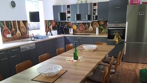 Une cuisine moderne avec une longue table à manger en bois, des meubles de rangement sombres et un four encastré.