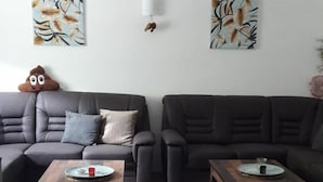 Un salon avec deux canapés, deux tables basses en bois et deux lampes fixées au mur.