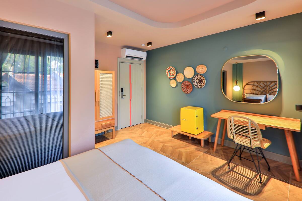 Una habitación de hotel moderna con cama, escritorio, silla y un espejo grande.