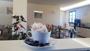 A dining area with tables and chairs, a white coffee cup with napkins and utensils, and a plant with red flowers. - Villa Nadar Hotel  B&B (Altopascio)