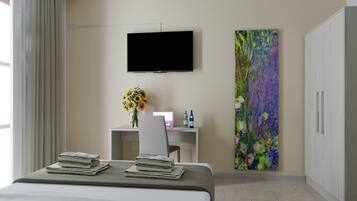 Quarto de hotel moderno com uma cama, uma escrivaninha, uma TV e um quadro floral grande.