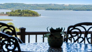 Blick auf einen See mit Tisch und Stühlen, einer Zierflasche und einer entfernten Insel.