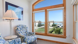 Ein Zimmer mit einem großen Bogenfenster, einem gerahmten Bild an der Wand und einem gemusterten Sessel.