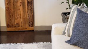 Un salon doté d’une porte coulissante de style grange, d’un canapé avec des coussins à rayures, d’un tapis blanc et de deux miroirs fixés au mur.