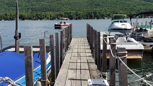 Une jetée en bois mène à un lac paisible, avec des bateaux amarrés sur la droite.