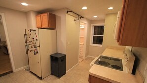 Cocina compacta con refrigerador, estufa y armarios de madera.