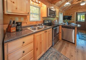 Eine hölzerne Kücheneinrichtung im Chalet-Stil mit einer Granit Arbeitsplatte, Edelstahlgeräten und Holzschränken.