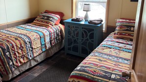 Une chambre avec deux lits, une fenêtre, une lampe sur une table de chevet et une porte.