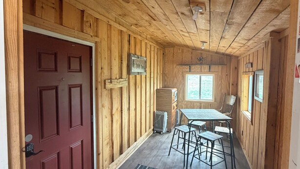 Un intérieur en bois avec une porte rouge, une table entourée de chaises et une fenêtre.