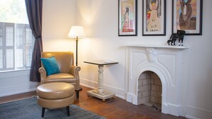 A living room with a fireplace, a sofa, a table, and framed artwork on the wall.