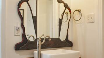 A bathroom with a white sink, a red cabinet, and a large mirror with an ornate frame.