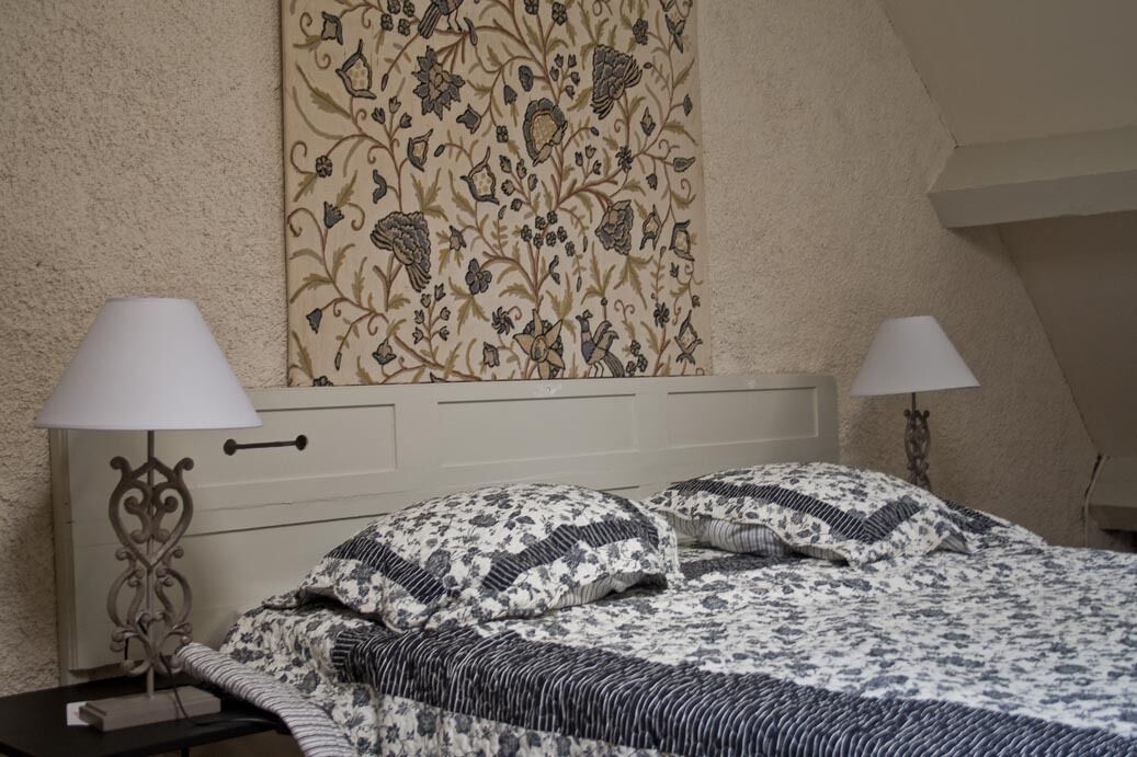 Een slaapkamer met een bed, twee bedlampen, een nachtkastje en een bloemenprint op de muur.
