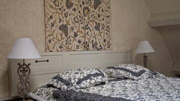 Een slaapkamer met een bed, twee bedlampen, een nachtkastje en een bloemenprint op de muur.