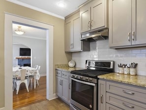 A modern kitchen with stainless steel appliances, grey cabinets, and a wooden dining area.