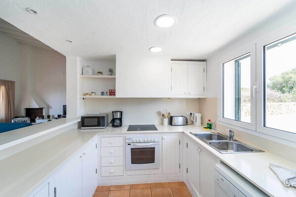 A compact kitchen with white cabinets, a built-in oven, a microwave, and a coffee maker.