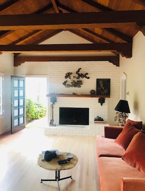 Cozy living room with a high ceiling, exposed beams, and a brick fireplace, perfect for relaxing.