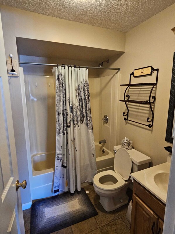 A bathroom with a shower, toilet, and sink.