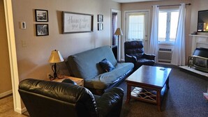 A living room with a sofa, a chair, a coffee table, and a fireplace.