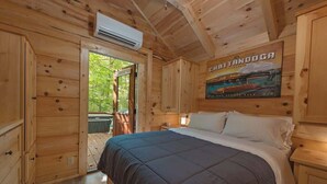 A wooden cabin room with a bed, a poster, and an air conditioning unit.